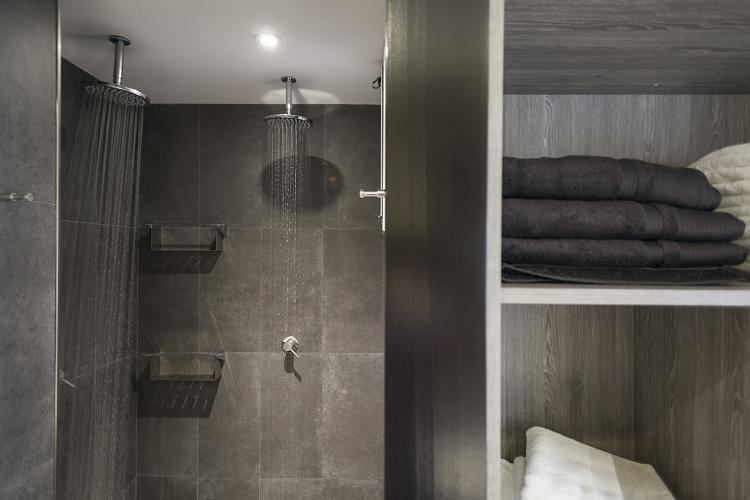 The bathroom comes with a modern rain shower and built.in shelves