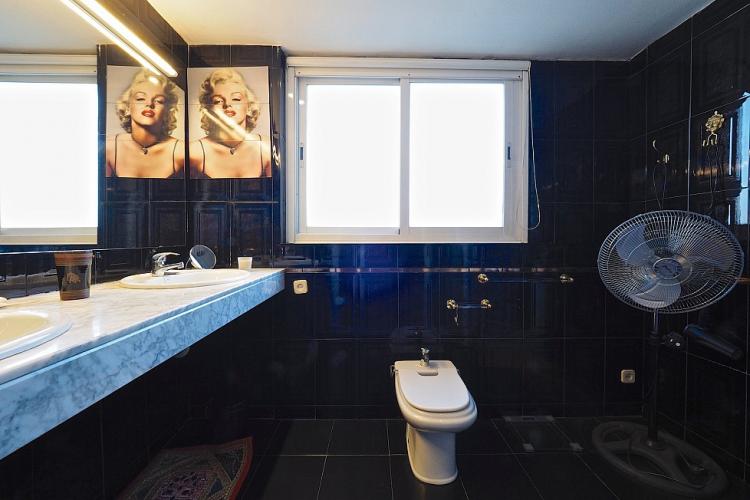 The bathroom is lined with smooth black tiles and decorated with a Marilyn Monroe theme.