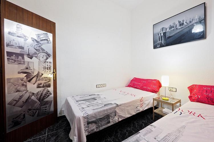 The room is decorated with classic black and white posters and comes furnished with two beds and a small bedtime table and lamp.
