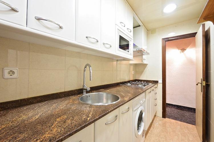 The modern kitchen is equipped with a microwave and stove top, as well as a washing machine.