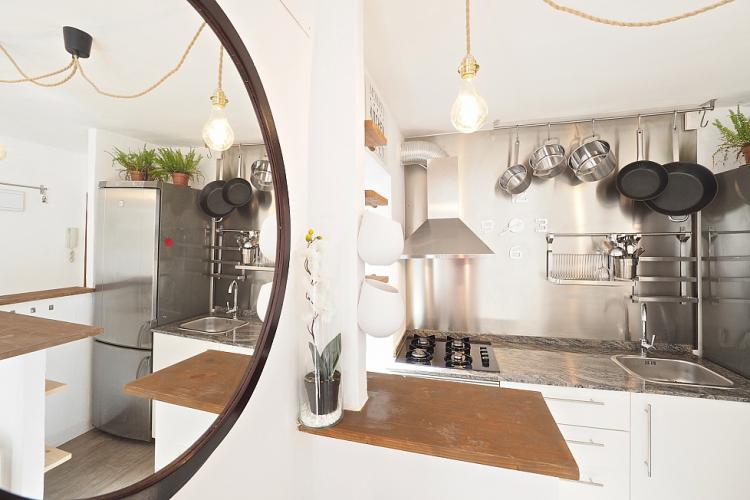 We love the small details throughout the apartment, such as this circular mirror and the industrial chic hanging lightbulb in the kitchen.