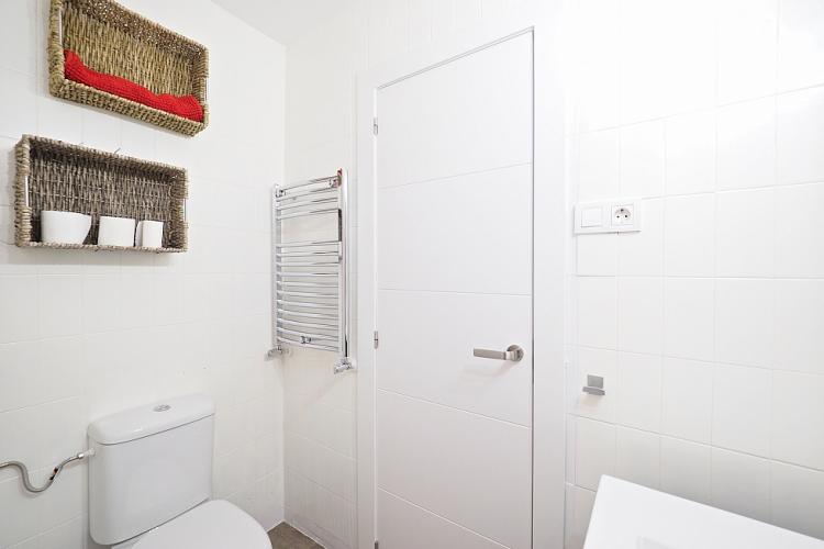 The bathroom comes adorned with bright white tiles lining the walls.