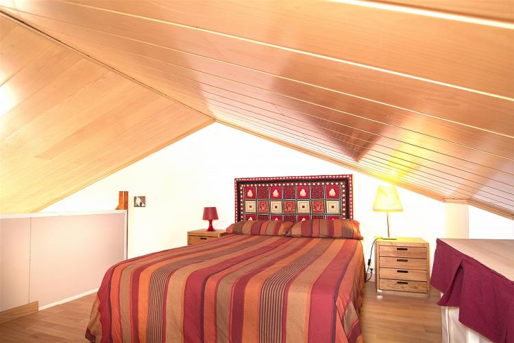 Master bedroom on the loft floor with smooth parquet floors and wooden panels in the ceiling.