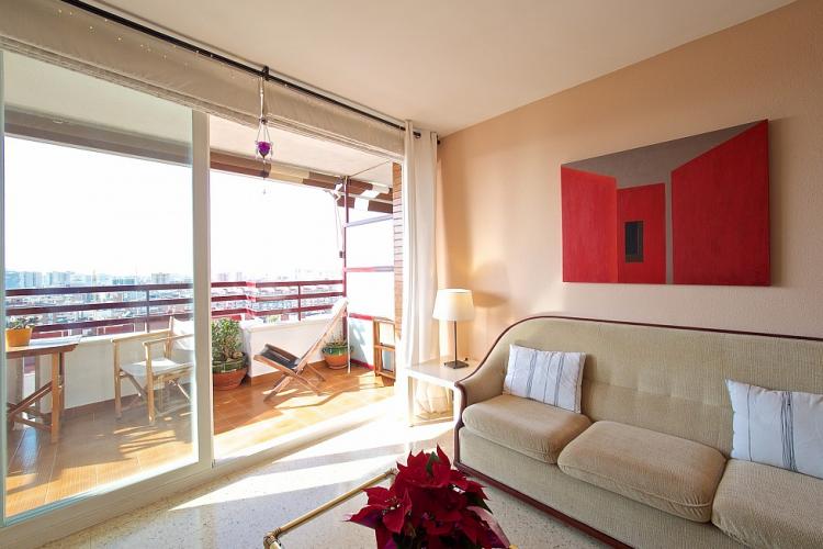 The living room has access to a spacious balcony furnished with a table and chairs.